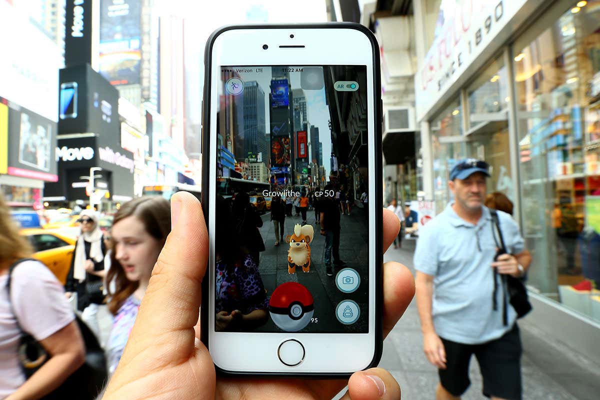 A user holding up their smartphone to show that a growlithe pokemon appearing in the middle of the busy street