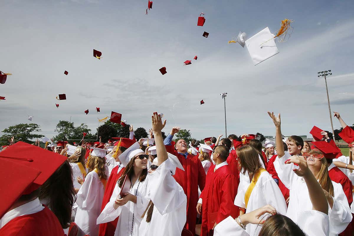 People at graduation ceremony fling their mortar boards in the air