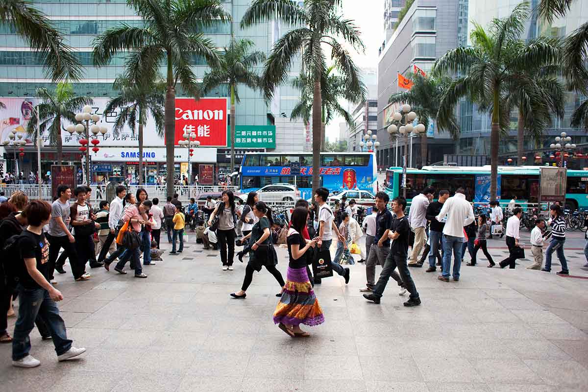 lots of people in a busy shopping mall, a woman in foreground looking at her phone