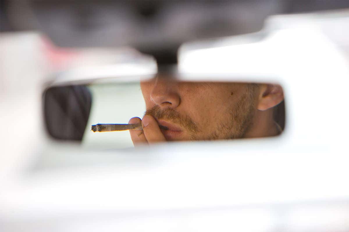 A man smoking a joint in a car