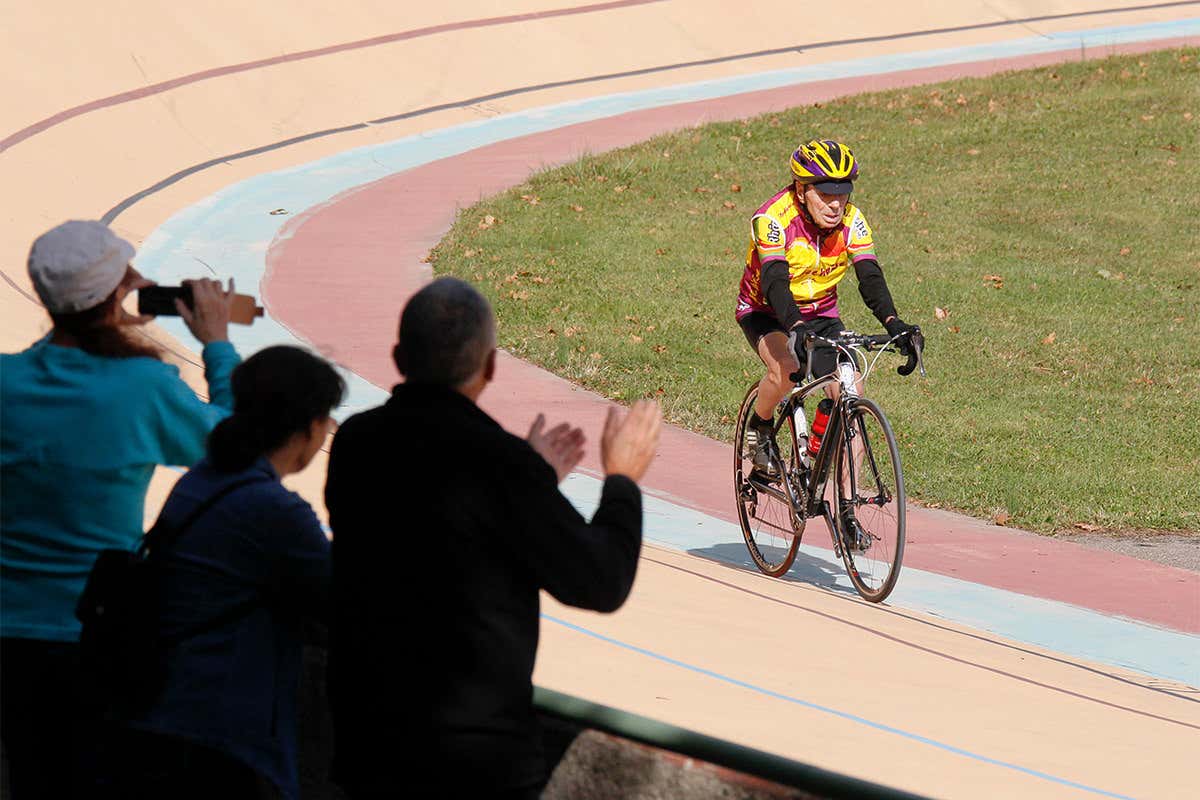 older man riding a bike around an outside track