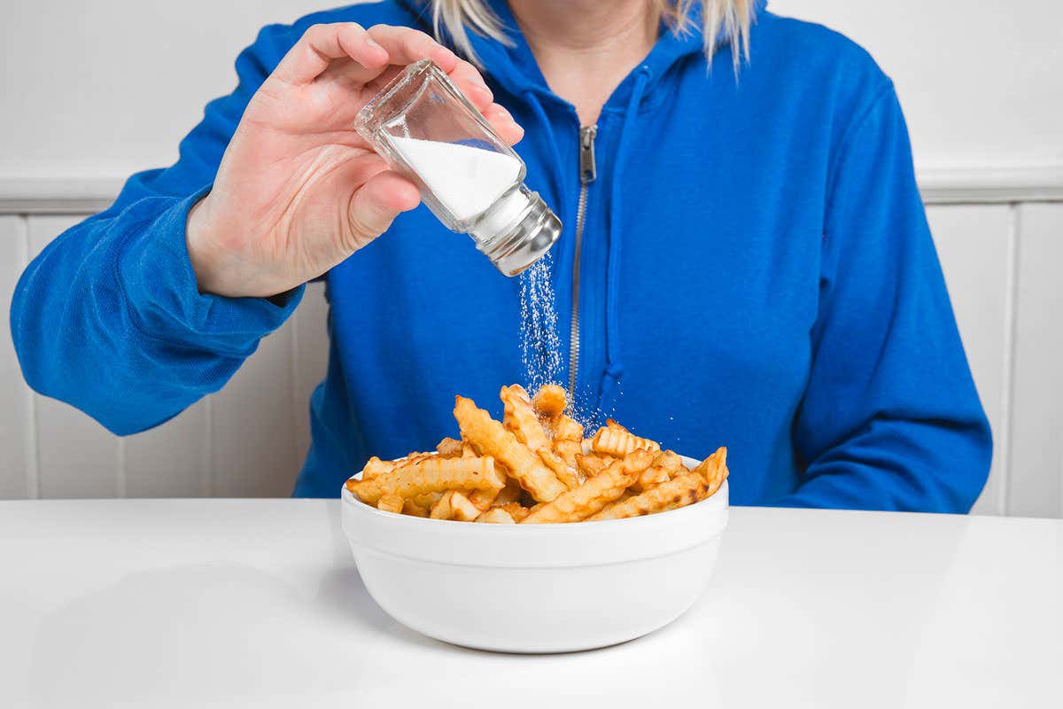 A woman adds salt to her chips