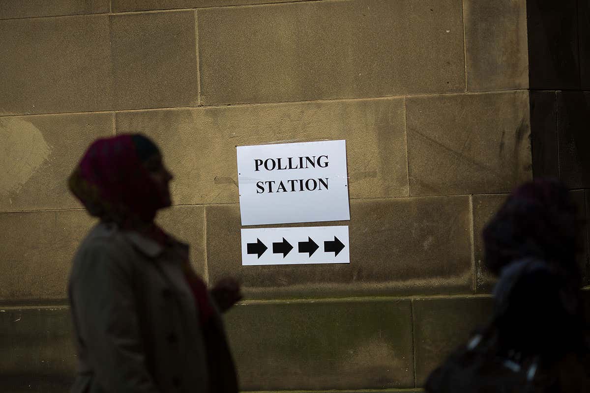 silhouette of a person next to a sign pointing the way to a polling station