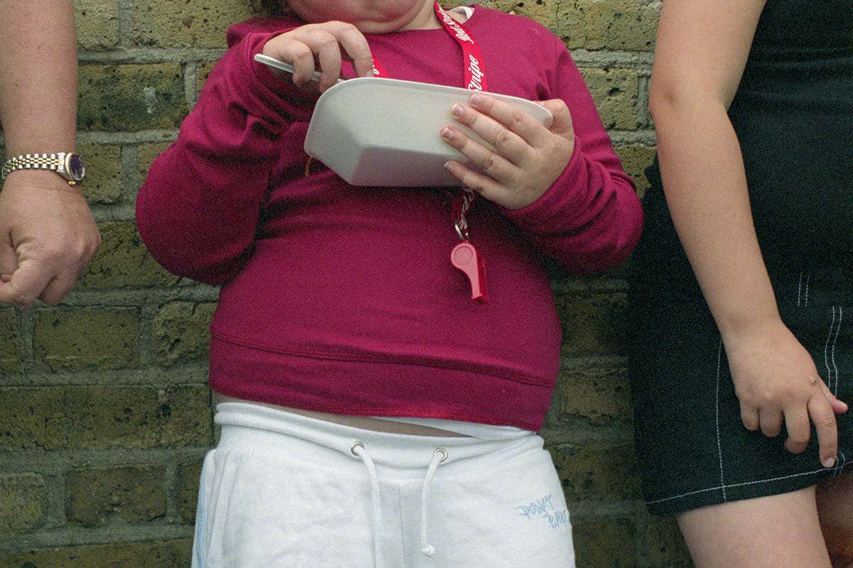 An overweight person eating takeaway food