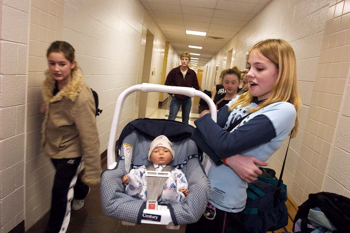 A girl with a doll that behaves like a baby