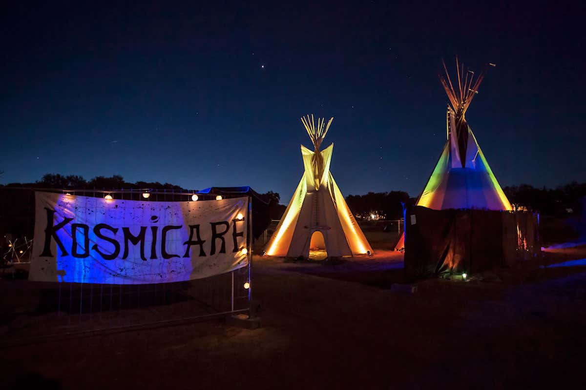 Kosmicare banner and teepees at night