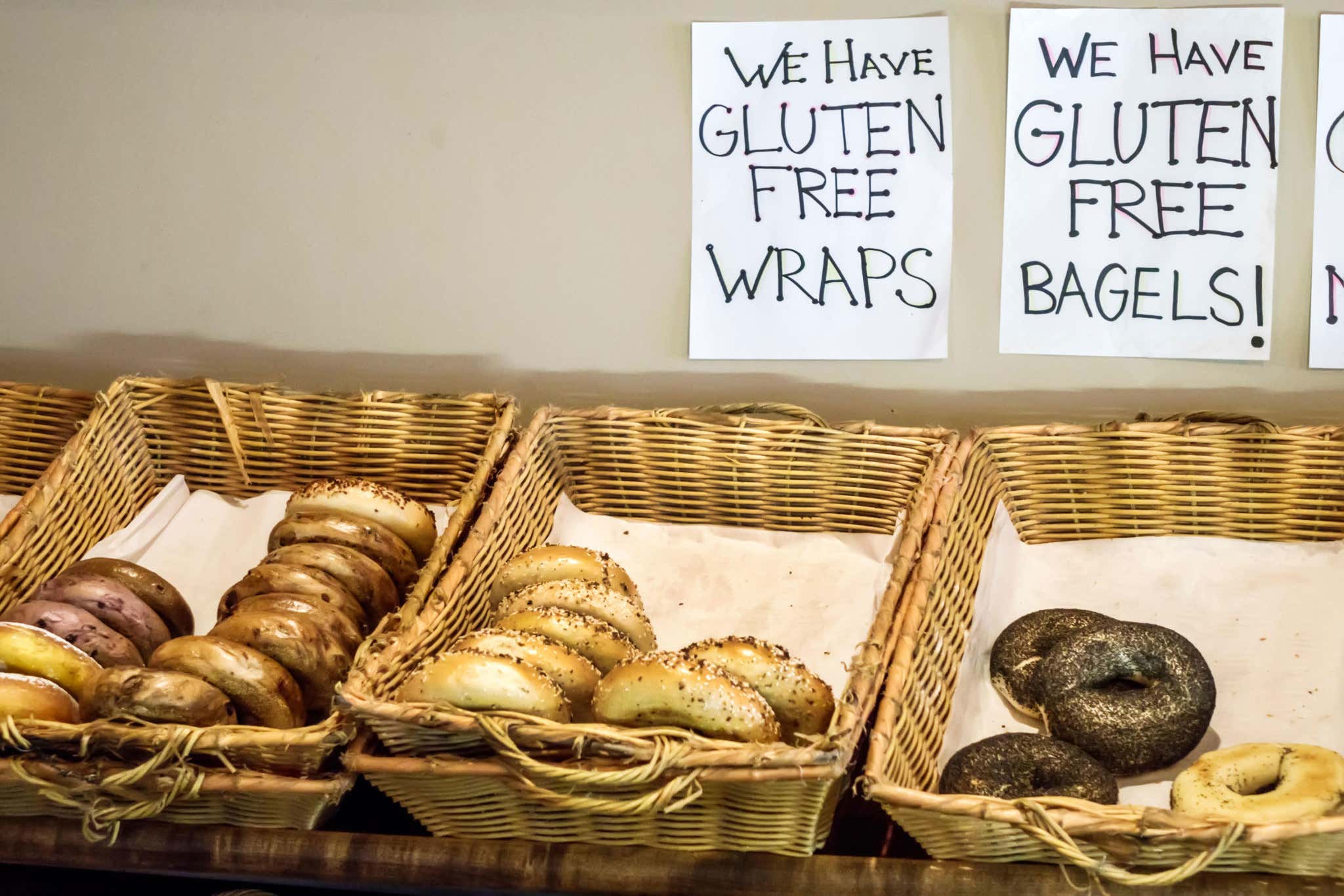 Bagels in baskets with sign above advertising gluten-free version