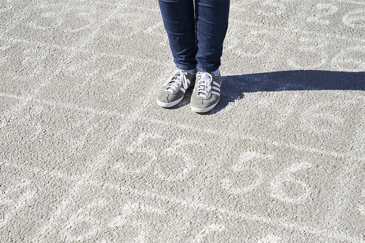 Numbers chalked on pavement with feet and legs in view