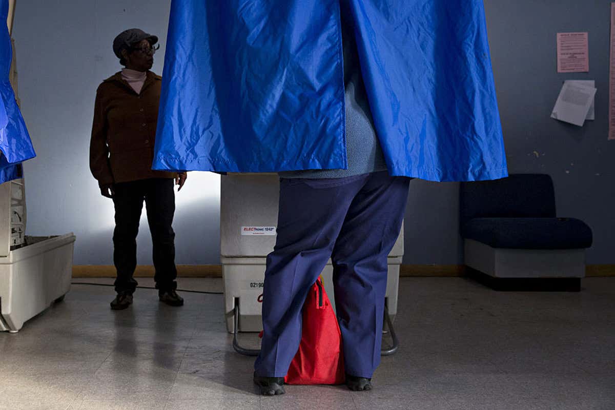 Picture of a man voting behind curtains to keep his vote a secret