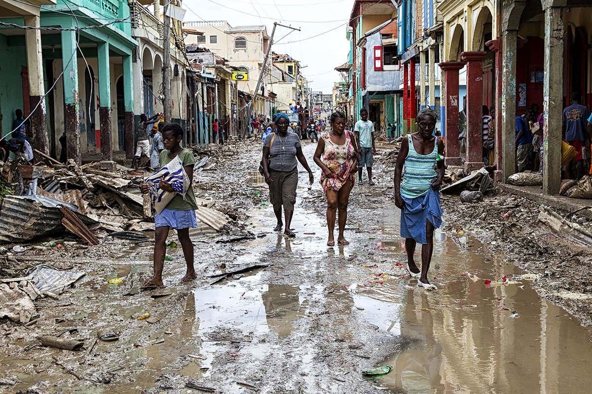 People walk down a flooded street in Haiti