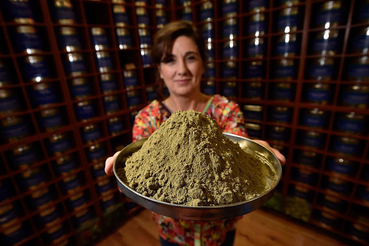 Woman holds platter of brown powder