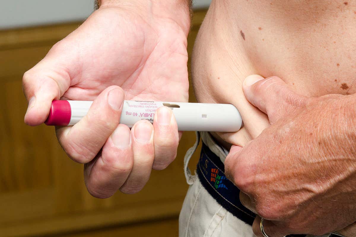 A person injecting themselves with the anti-inflammatory drug Humira