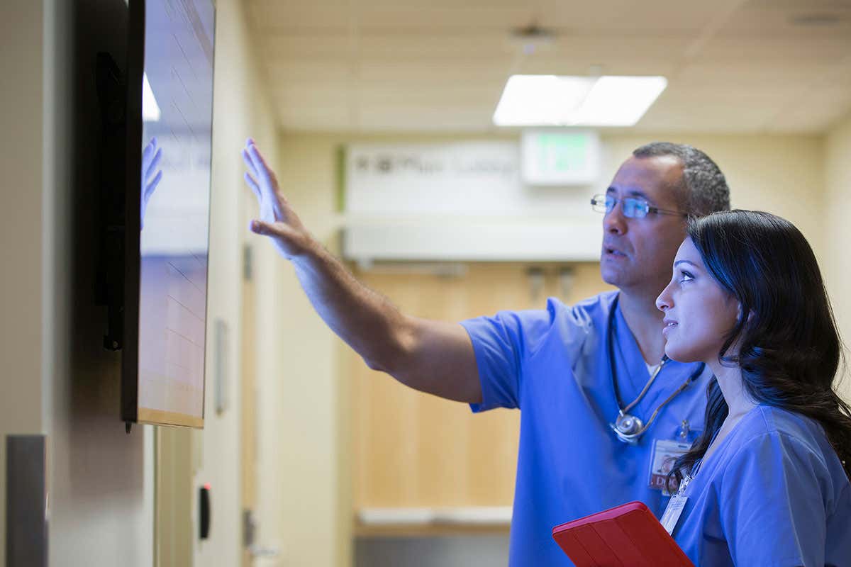Doctors looking at monitor in hospital cocrridor