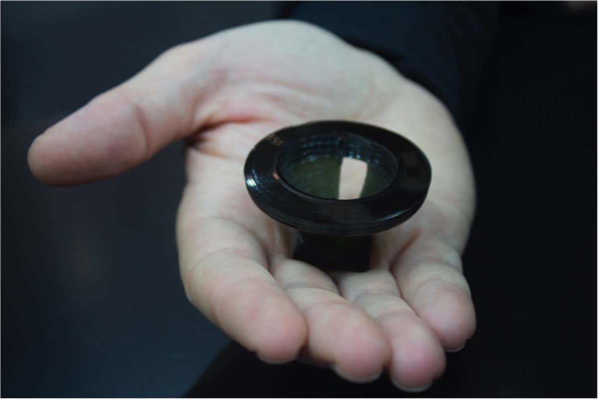 Someone holds a small black plastic cup shape on the palm of their hand
