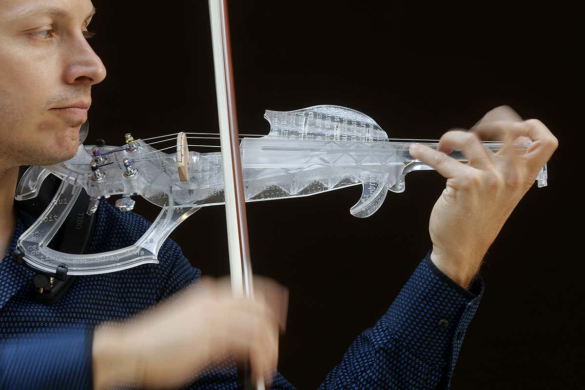 A man playing a violin made out of a frosted white material. The body of the instrument is more like a frame than a traditional violin body, with large open sections