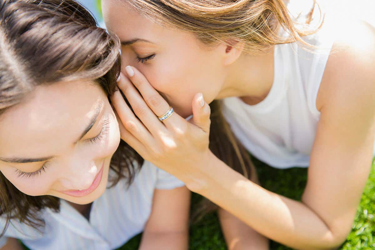 One girl whispers in another's ear