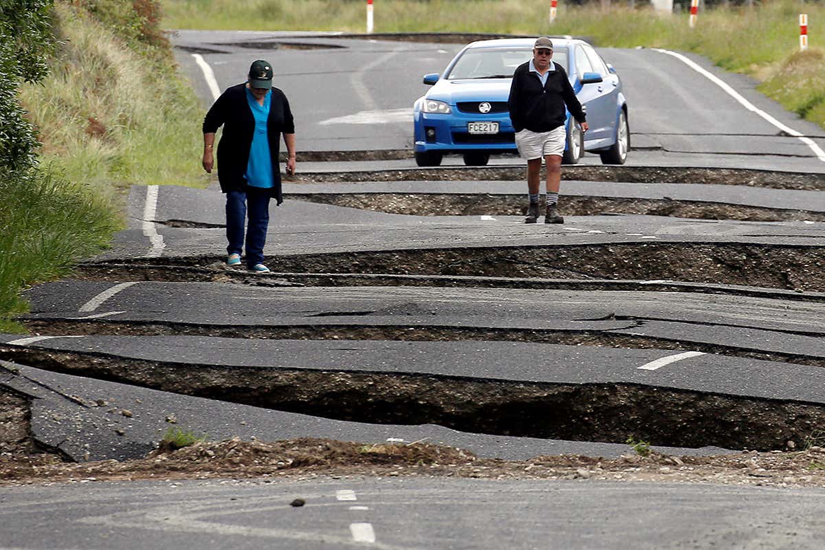 People survey damage to a buckled road