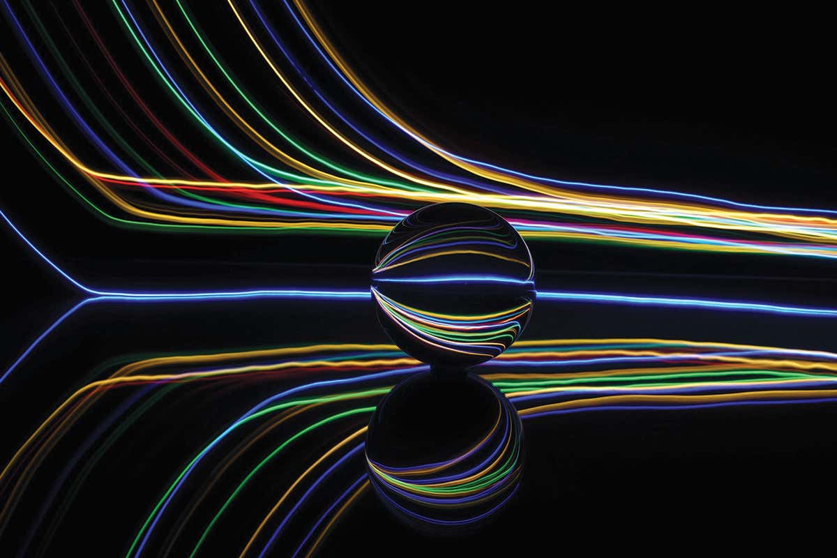 Colourful lines of light against a black background skirt around a marble