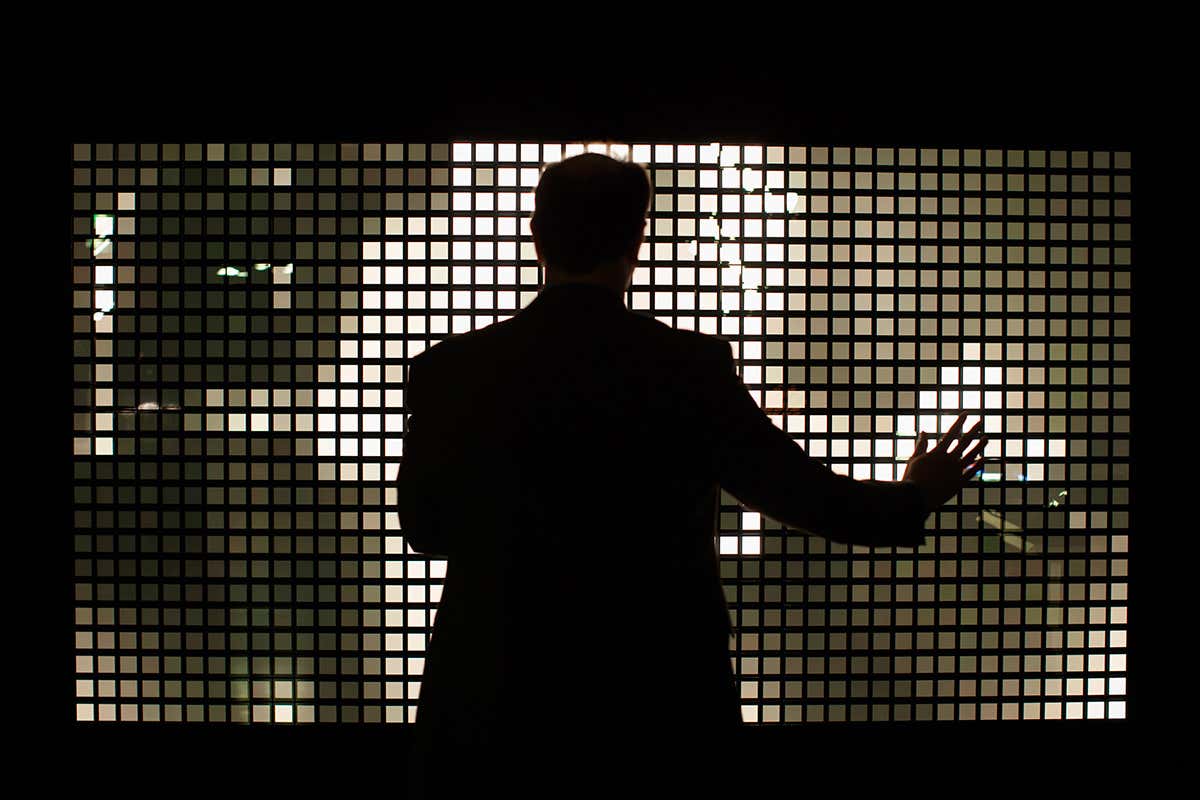 A shadowy figure stands in front of an array of square lights