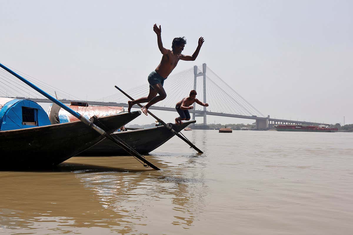 Two boys jumping from a boat into the Ganges river