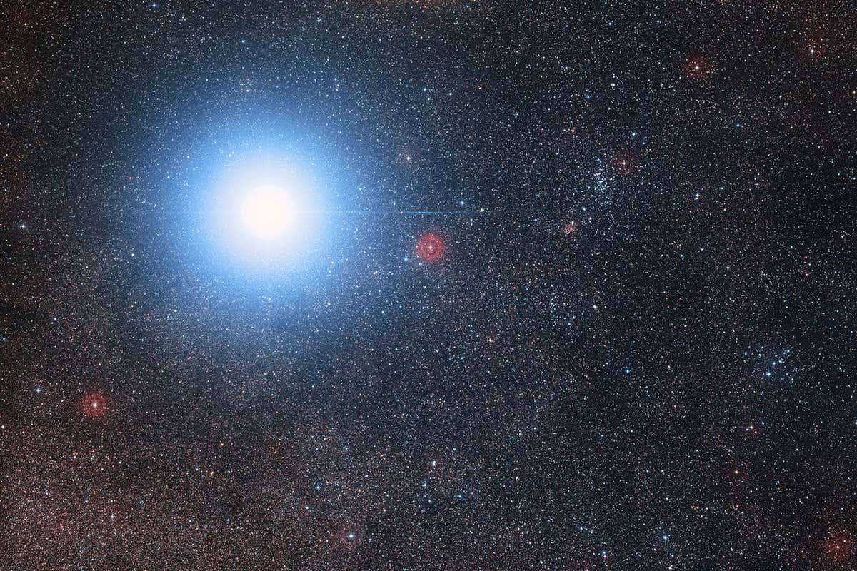 A faint red star can be seen next to a mich brighter pair of stars that appear as one