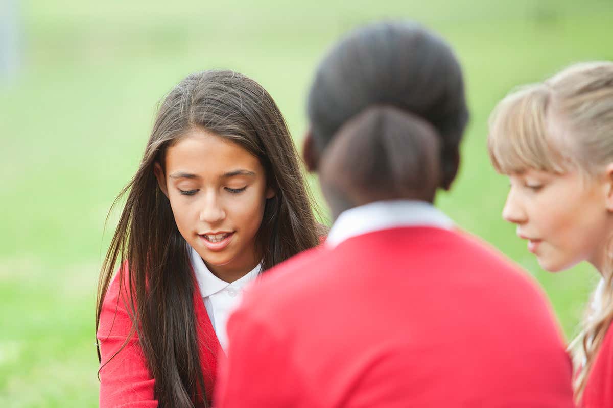 Two school girls talking, one facing away from the camera