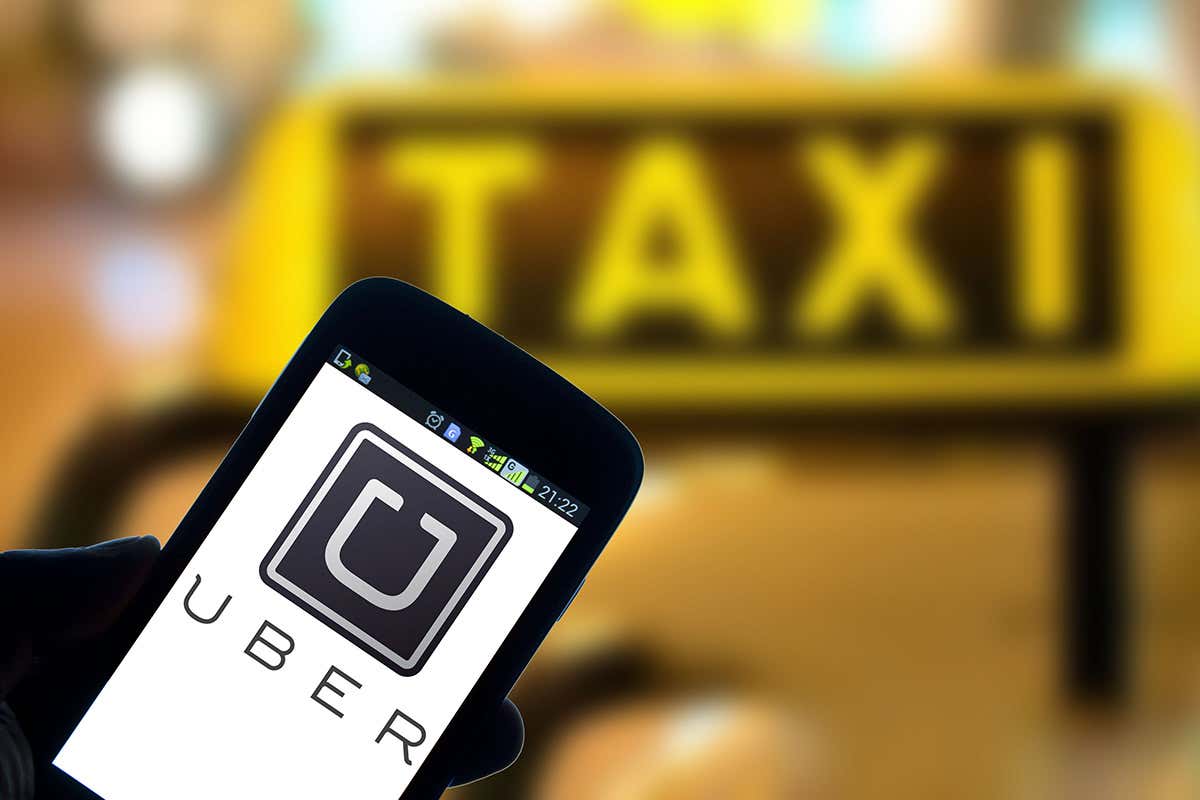 Uber app on smartphone in front of taxi