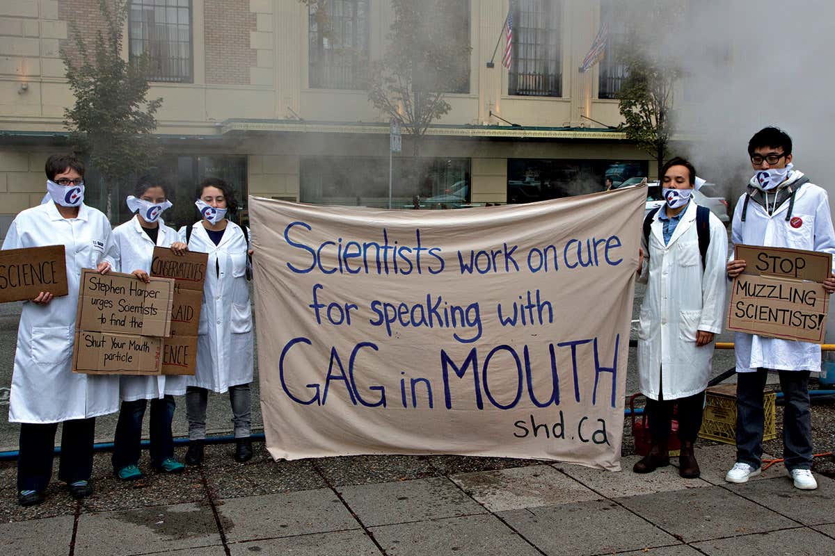 People in white lab coats hold banner reading