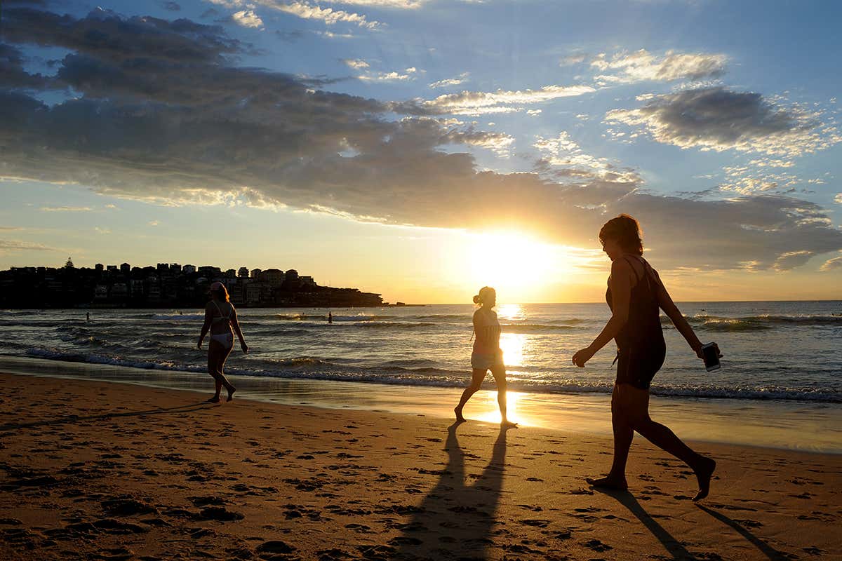 People on beach with sun low in the sky