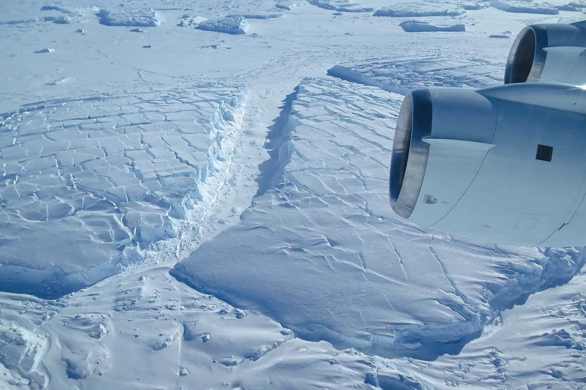 The wing of a plane flying oer Antarctic ice