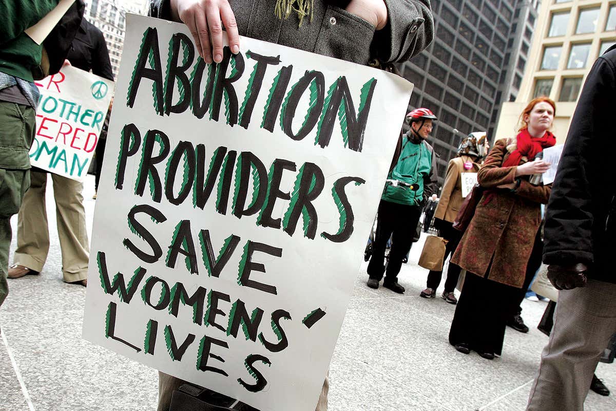 person holding a banner saying'abortion providers save womens' lives'