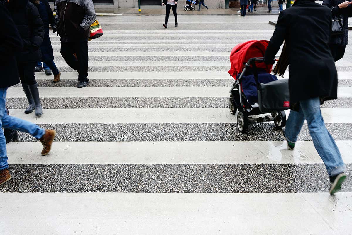 A pram being pushed across a zebra crossing