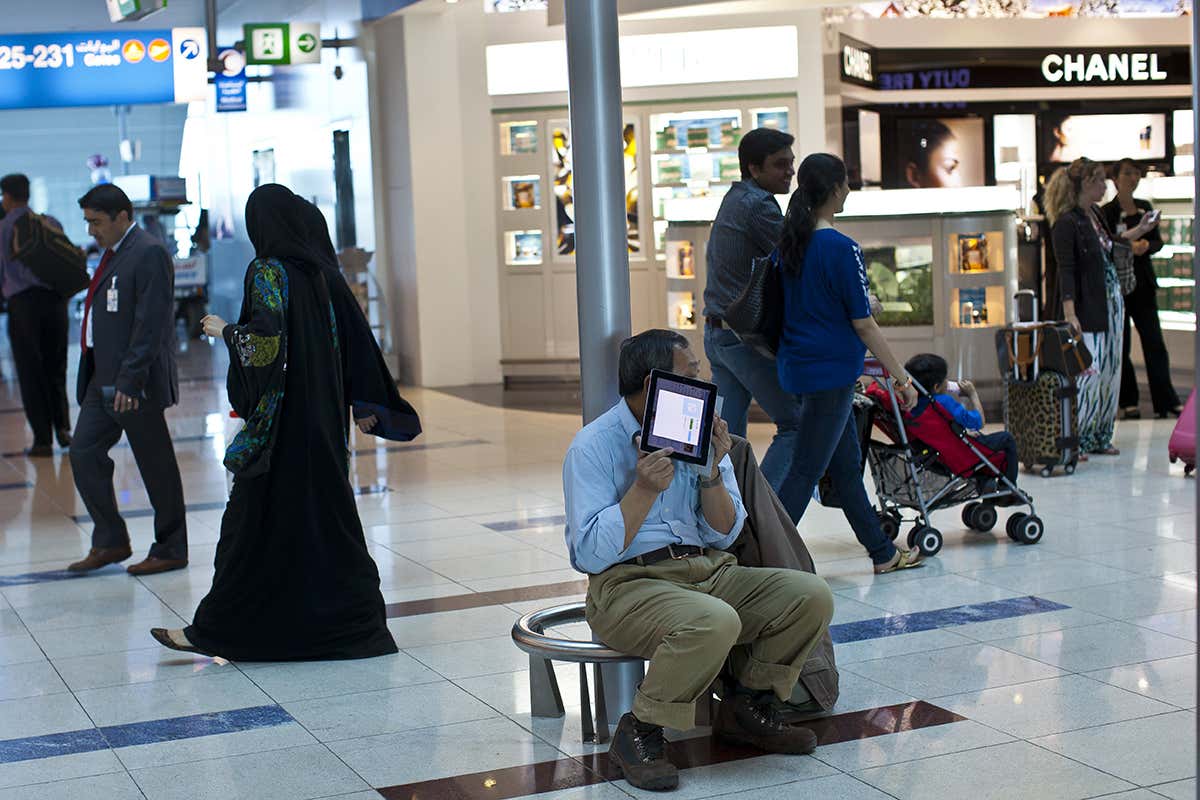 A man holds an electronic tablet in an airport waiting room
