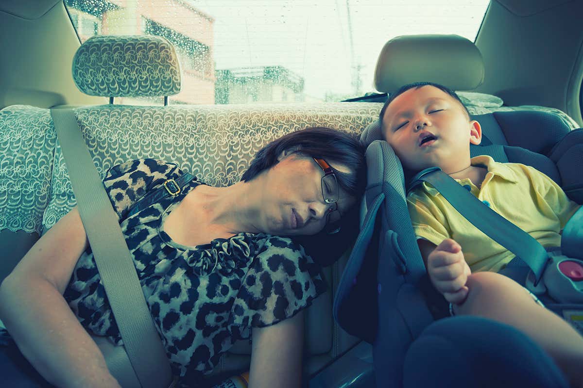 Two people asleep in the back of a car, possibly dreaming