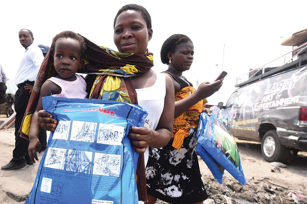 A woman holding a child and a mosquito net package