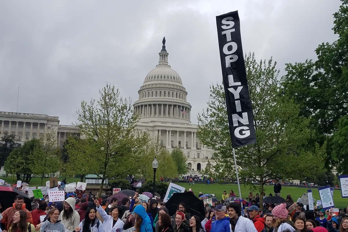 Marchers in front of the Capitol Building in Washington, DC, with a sign saying 
