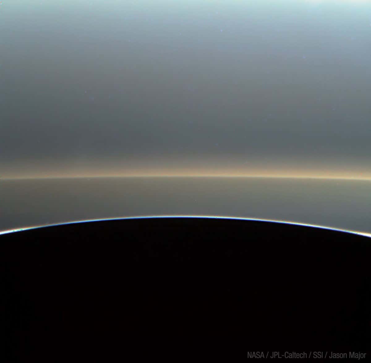 Processed image of Saturn's outer rings viewed over the planet's dark horizon