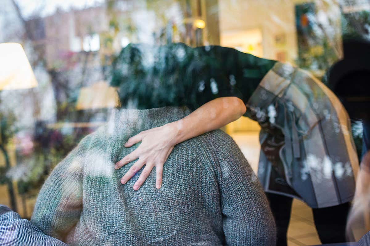 Woman with hand on person's back