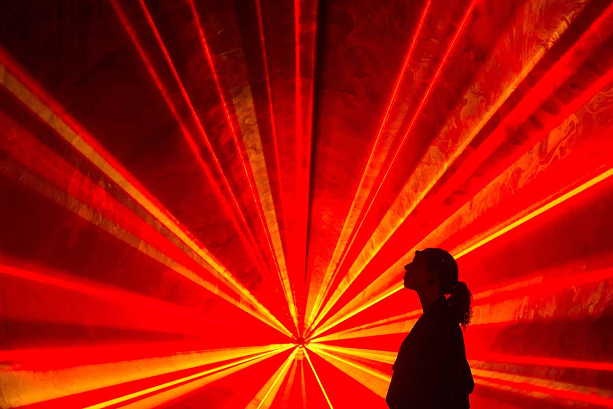 A person silhouetted against a fan of red laser light