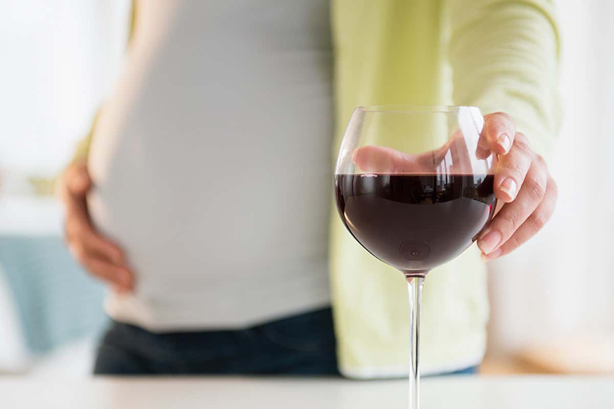 A pregnant woman with a large glass of red wine