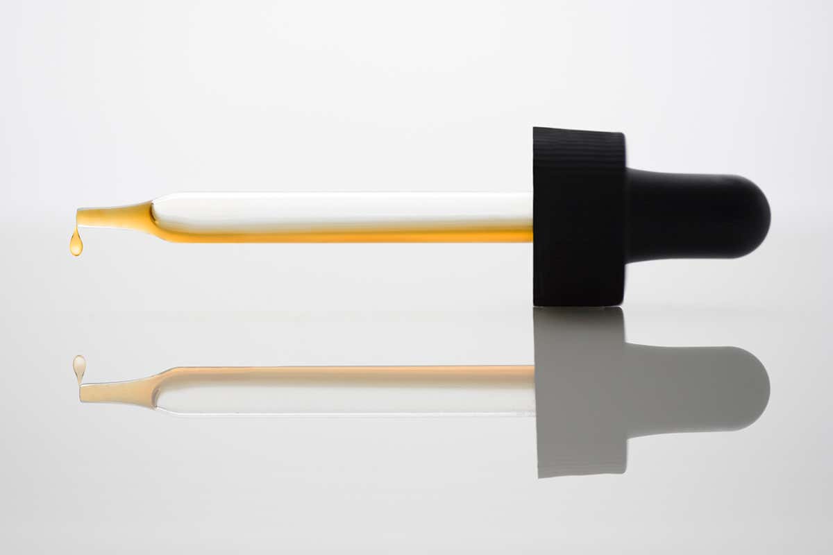 A pipette dripping a gold coloured liquid