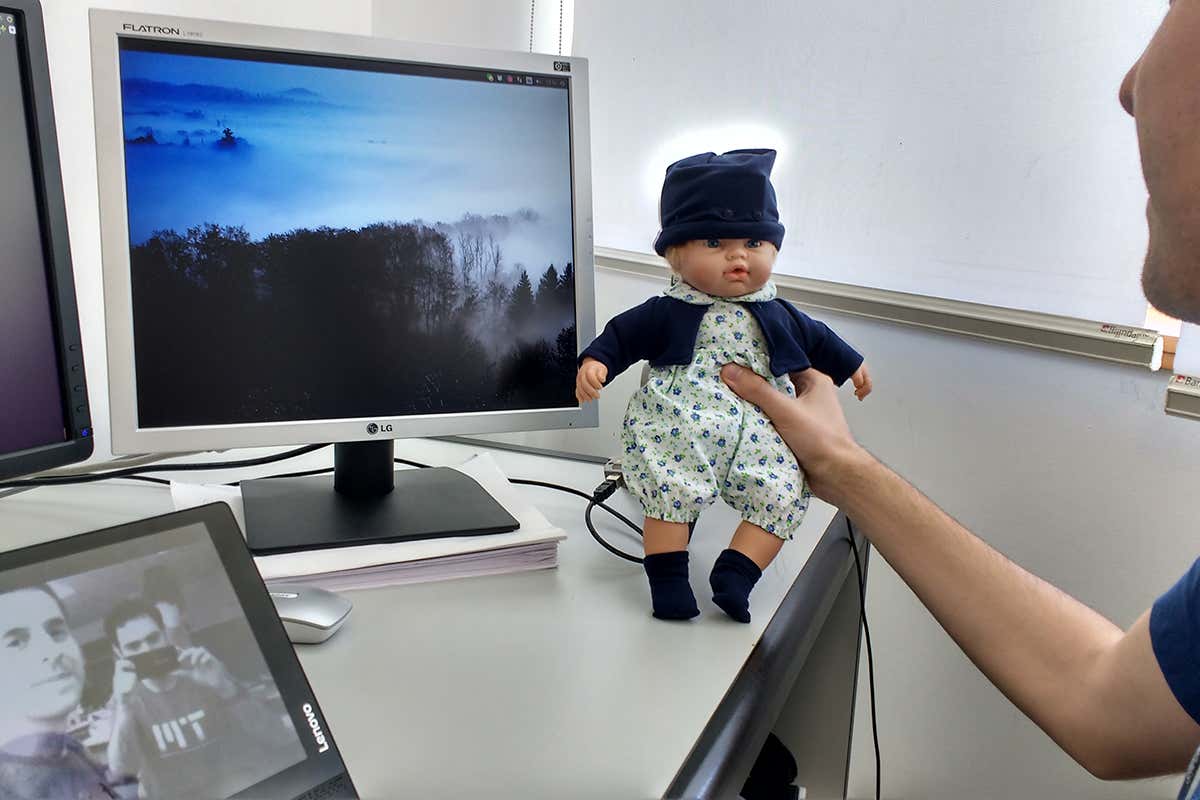 Man holds doll next to computer screen