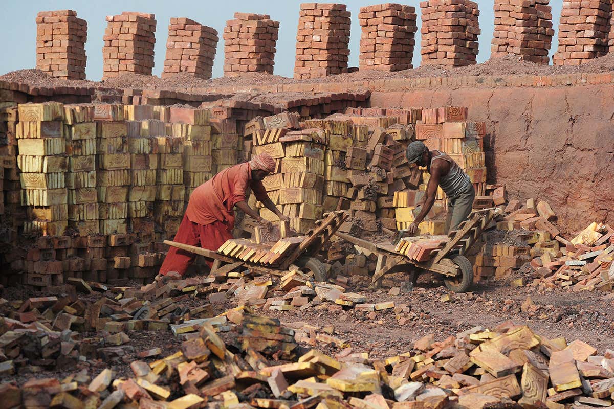 Slave labourers piling red bricks into trolleys