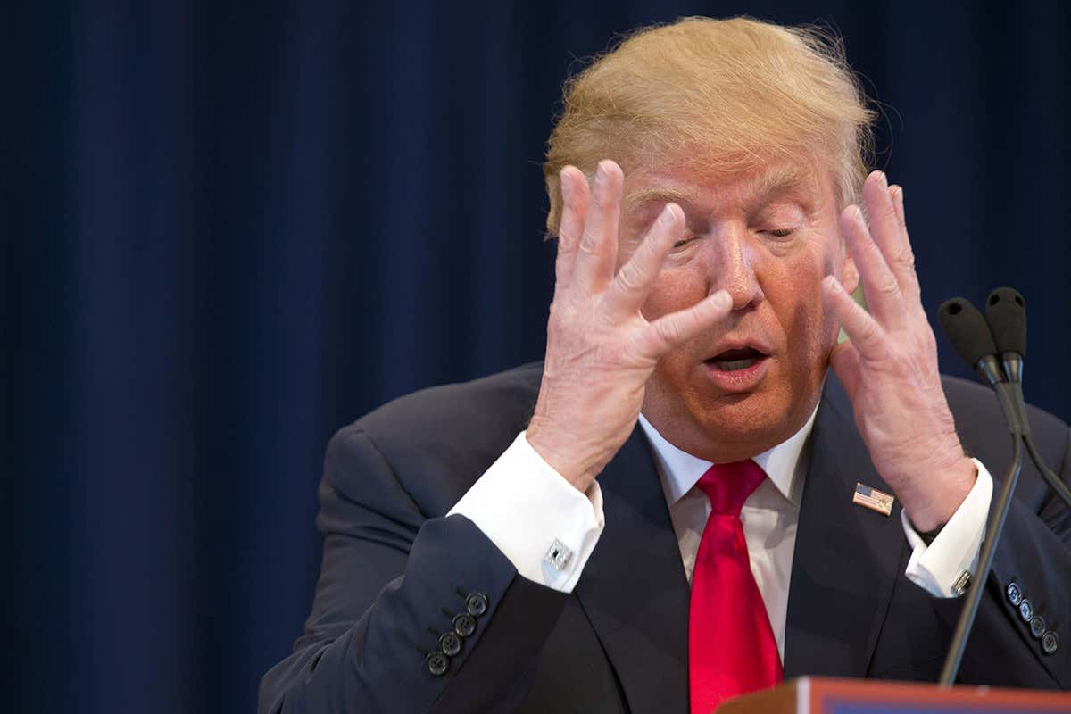 Donald Trump with his hands up covering his face