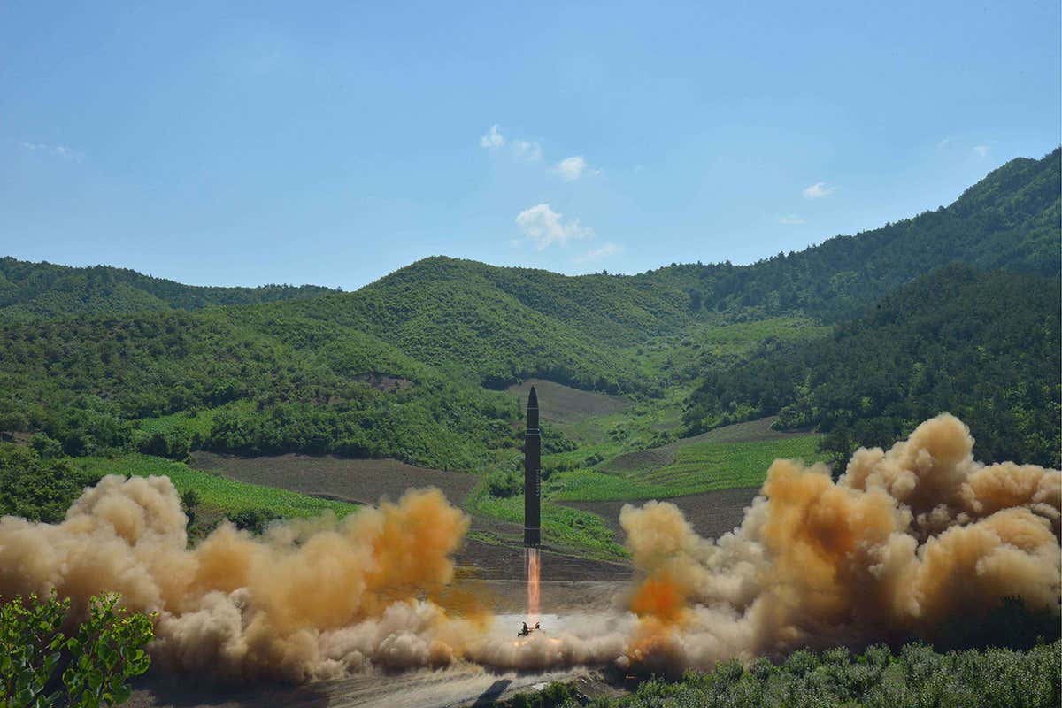 A missile blasts off again the background of green hills