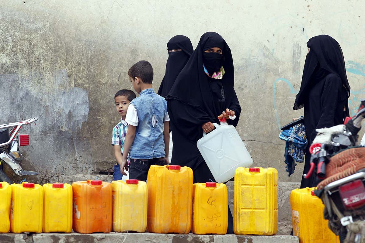 Yemeni women wait to fill jerrycans with drinking water