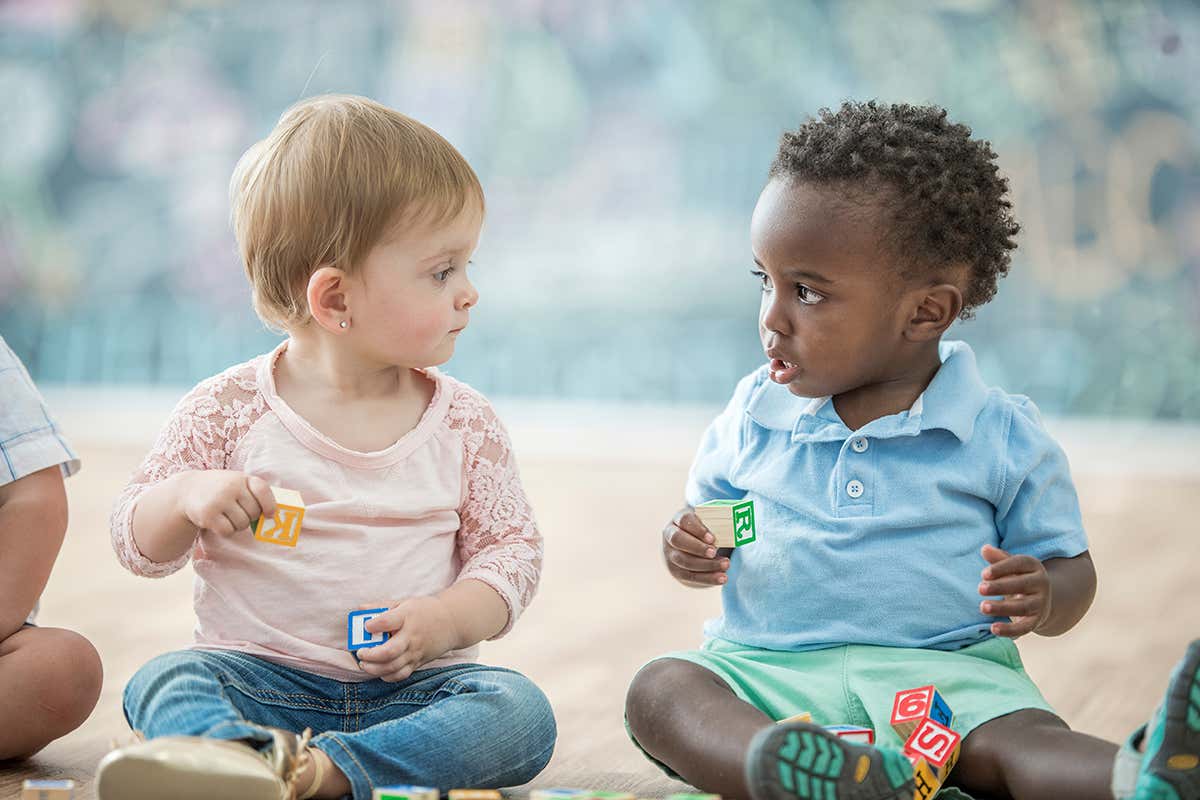 Babies play in a daycare together. They play with blocks