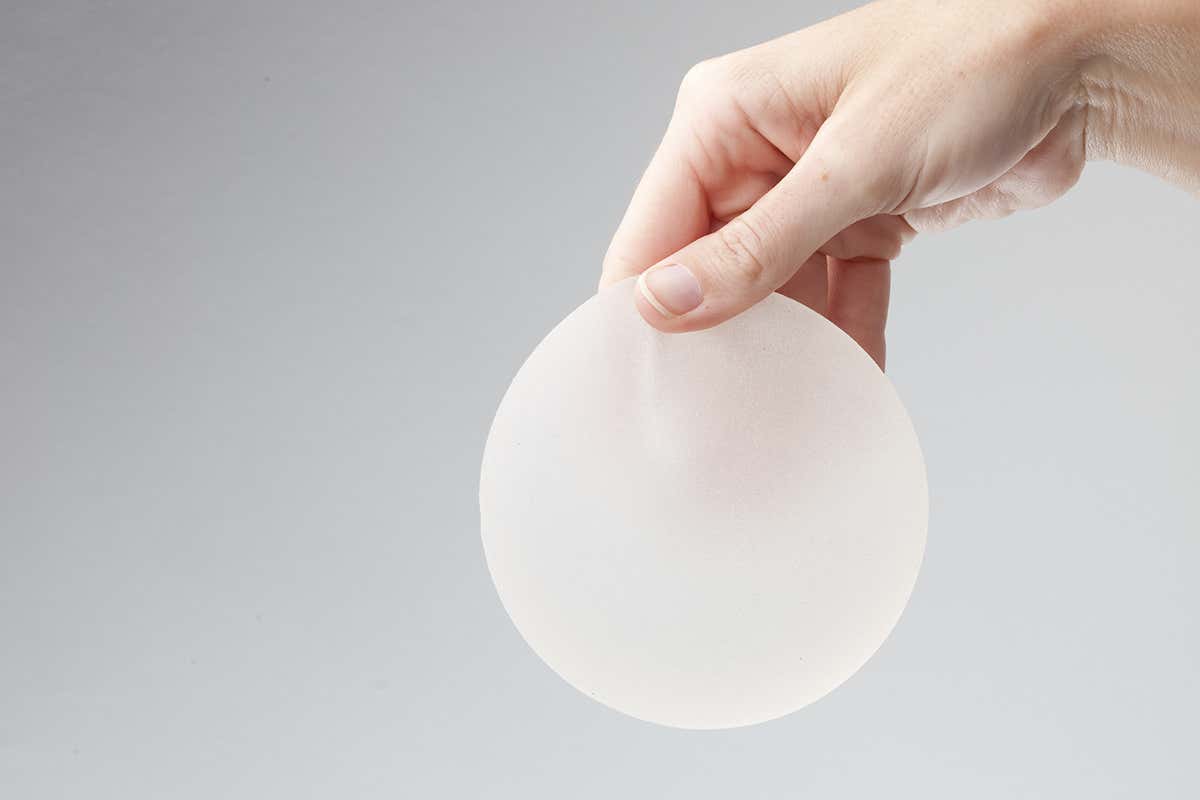 A hand dangling a breast implant