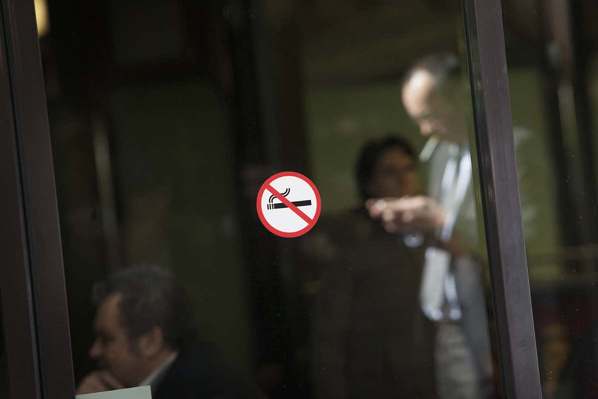 A man behind a no smoking sign