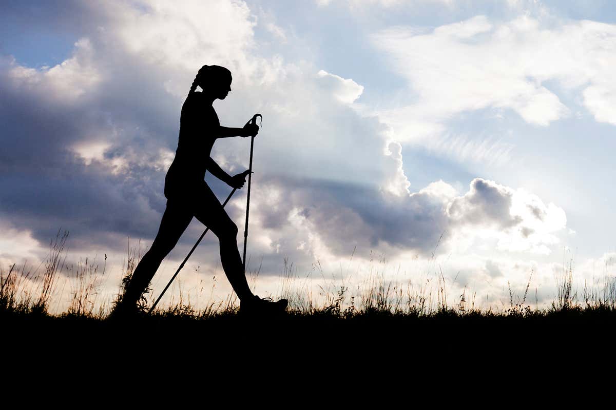 Woman walking againt the skyline with walking poles